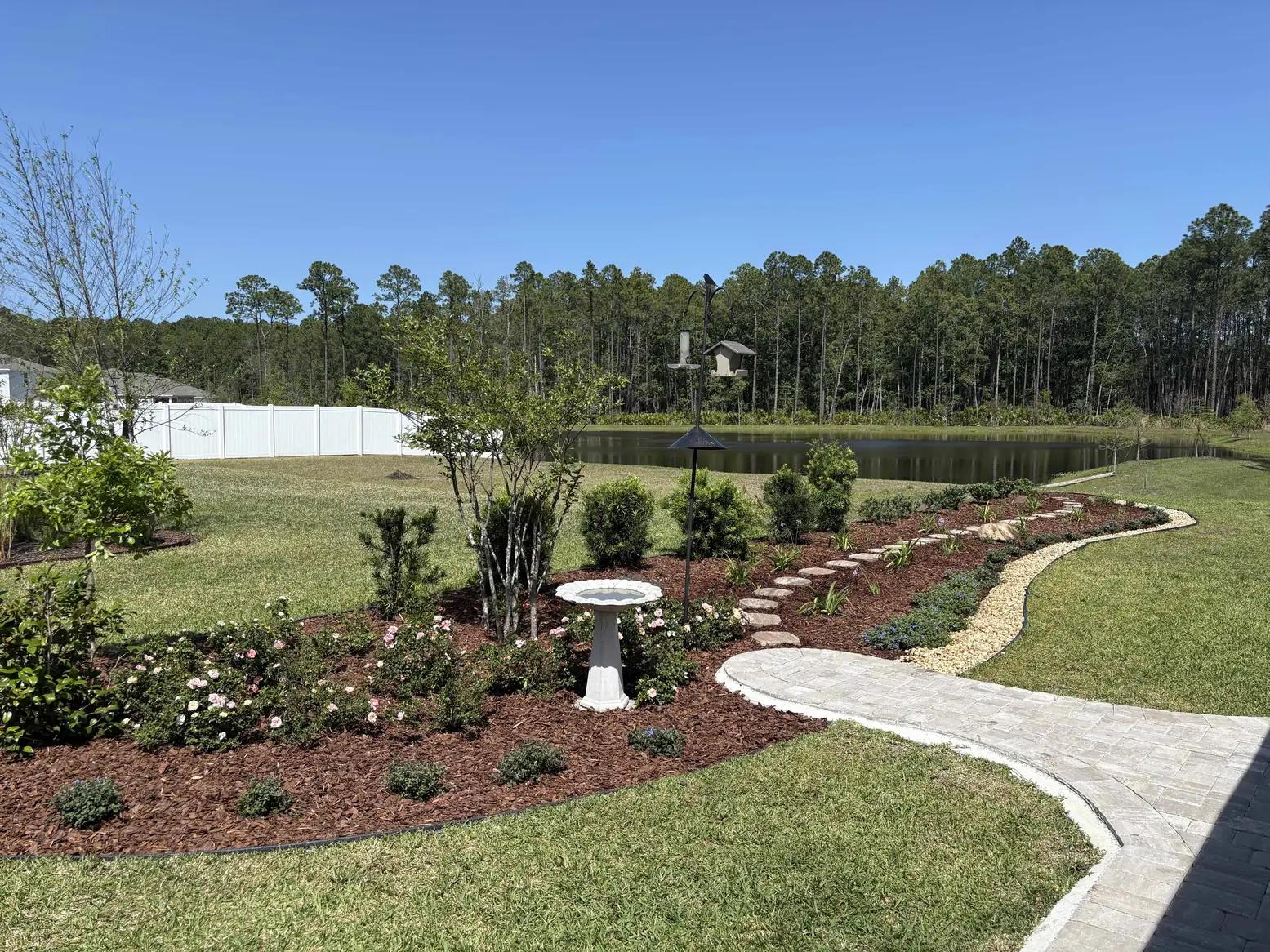 Landscape design with curved garden beds, a stone path and lakefront lawn in St. Johns County, FL