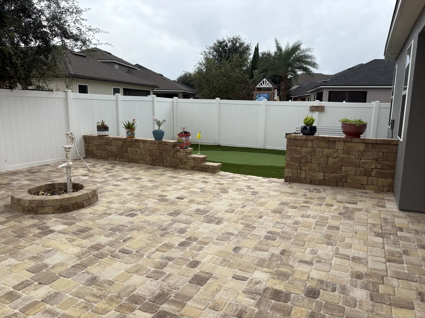 Paver patio with block retaining wall planters, artificial turf and a putting flag in St. Augustine, FL