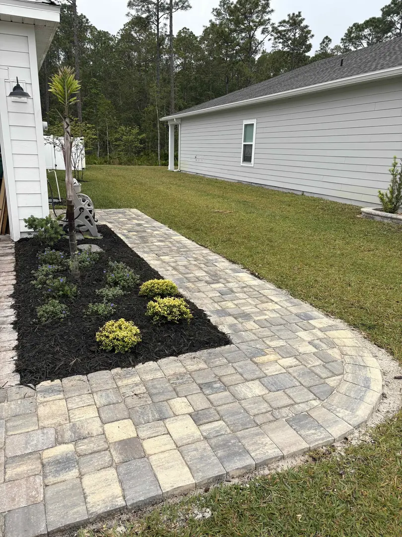 Curved paver walkway and mulch bed running along the side of a home in St. Augustine, FL