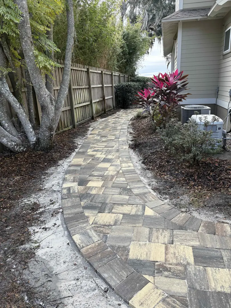 Freshly laid paver walkway curving along a side yard in St. Augustine, FL