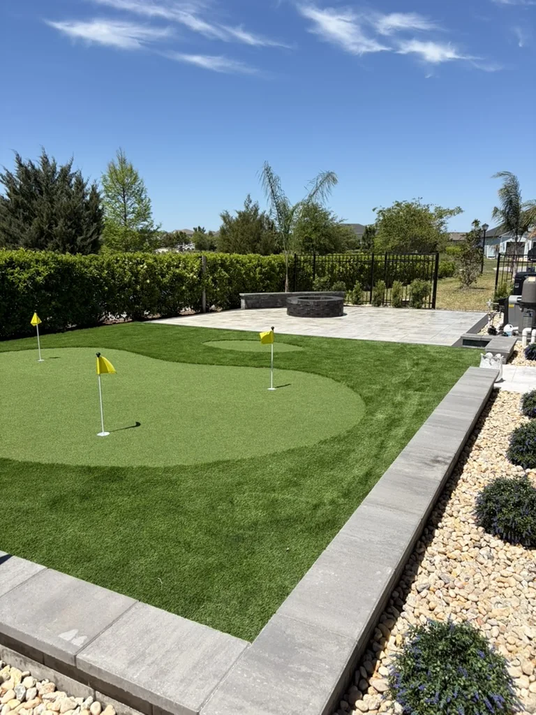 Backyard putting green with a paver border and river rock edging in St. Augustine, FL