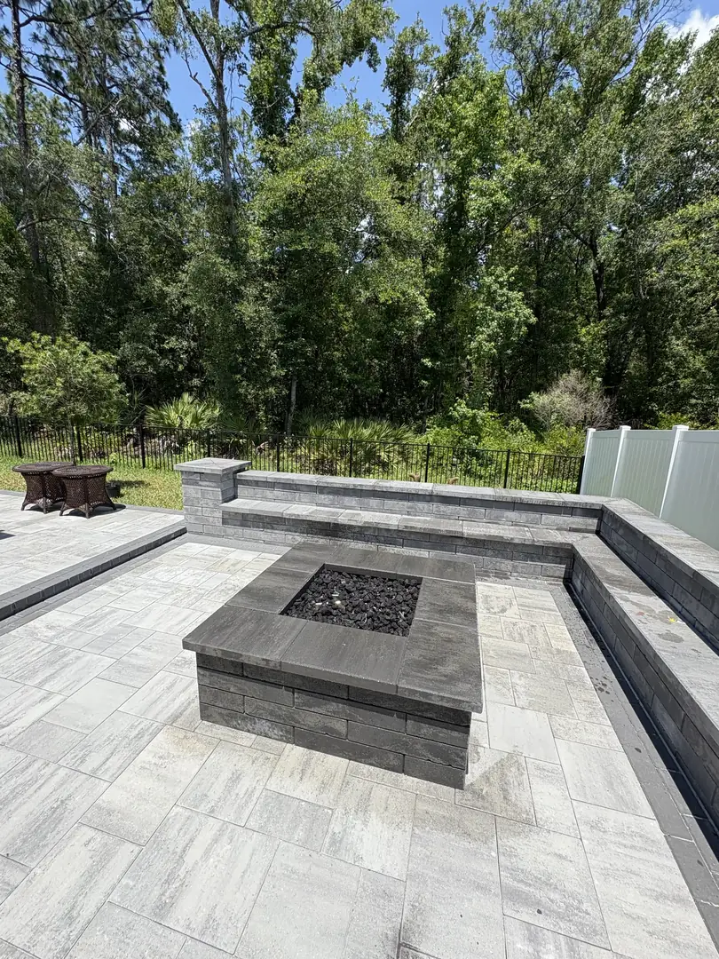 Travertine paver patio with a rectangular gas fire pit and an L-shaped seating wall